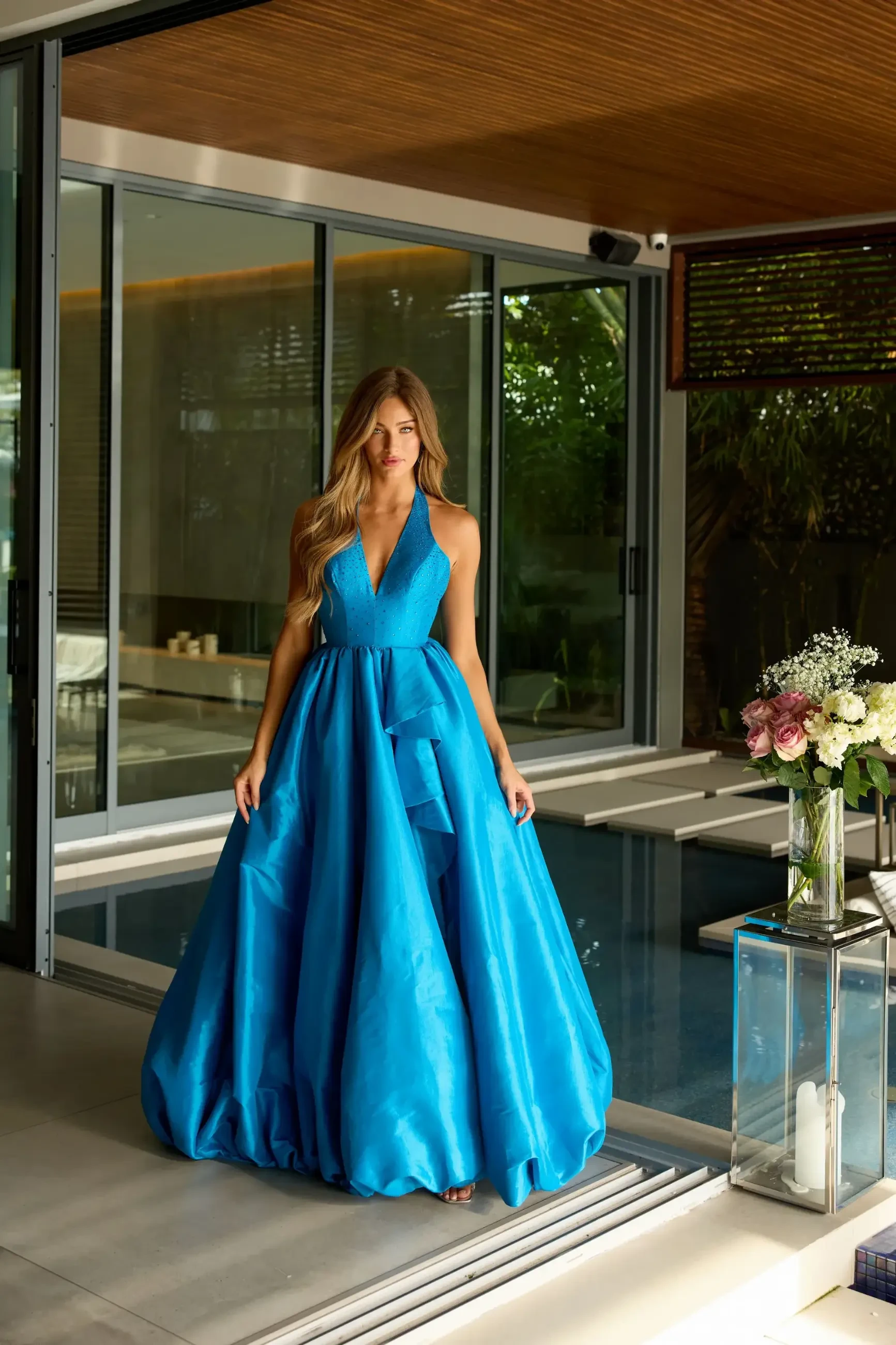 Model is wearing a sleeveless halter blue ball gown for prom 2026
