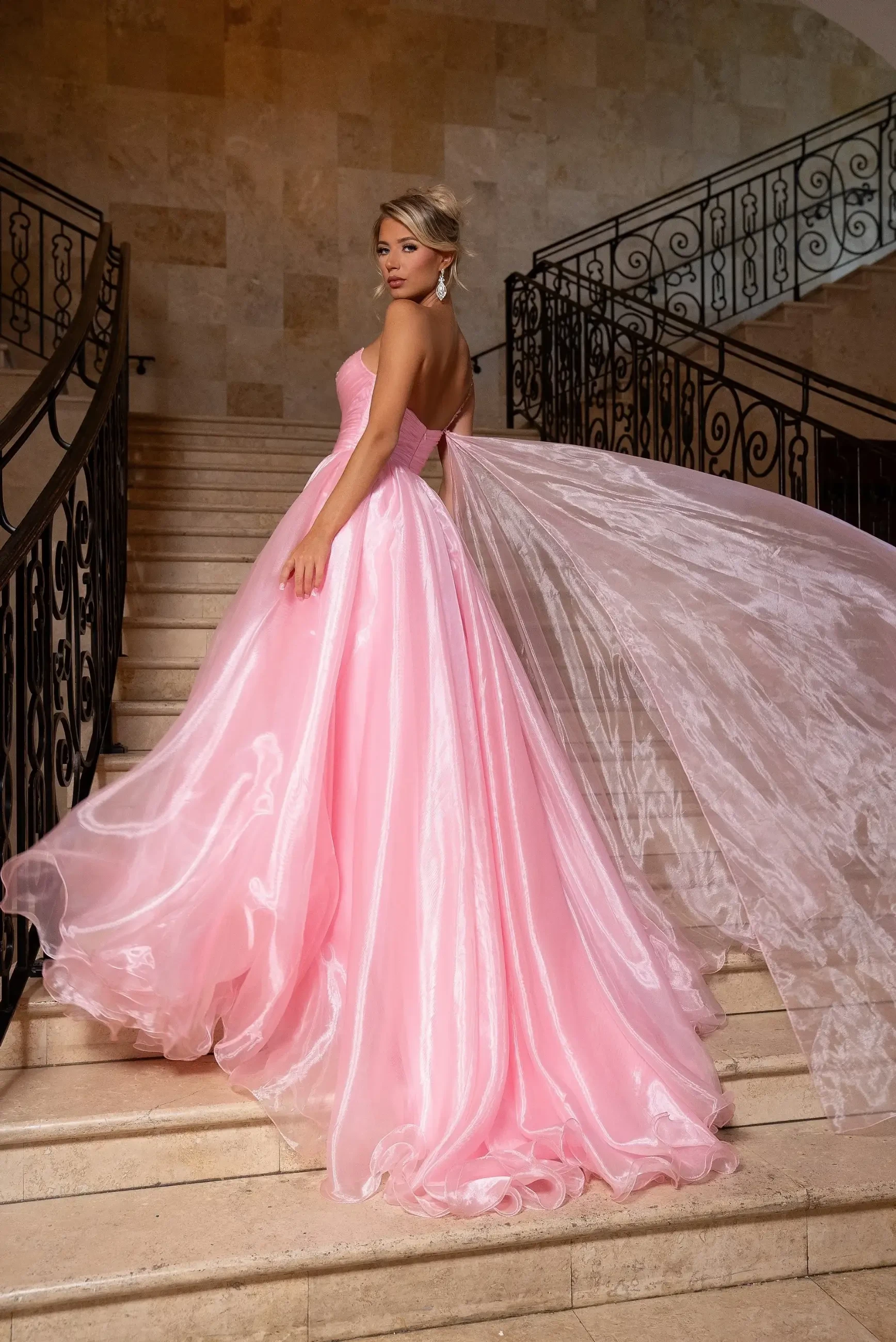 Model is wearing a pink a-line evening gown with a one shoulder beaded bodice