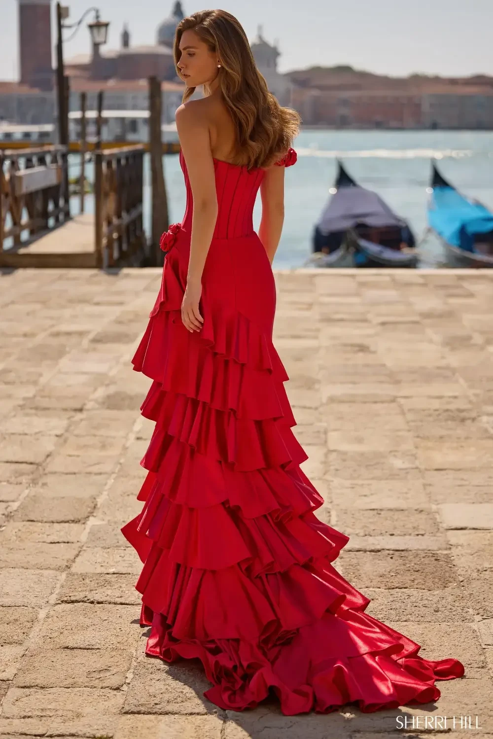 model is wearing a red tiered off the shoulder prom dress
